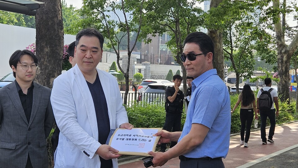 응급의학과의사회 이형민 회장은 대통령실 관계자에게 책과 편지를 전달했다(ⓒ청년의사).