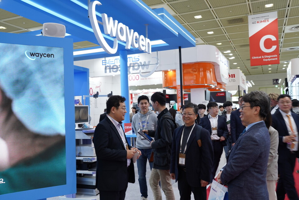 웨이센 김경남 대표(맨 왼쪽)가 웨이센 부스를 방문한 국무조정실 정병규 규제혁신기획관(맨 앞줄 가운데)에게 제품을 설명하고 있다(웨이센 제공). 